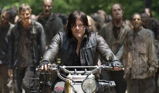 Daryl riding on motorcycle with a horde of zombies behind him.