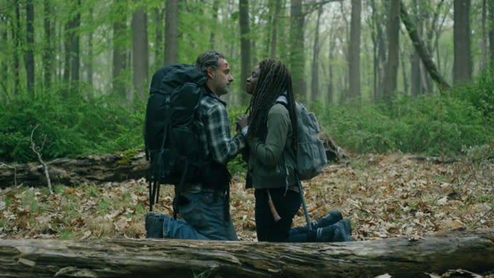 Rick and Michonne in plainclothes with backpacks kneeling and facing one another in a forest on The Walking Dead: The Ones Who Live.