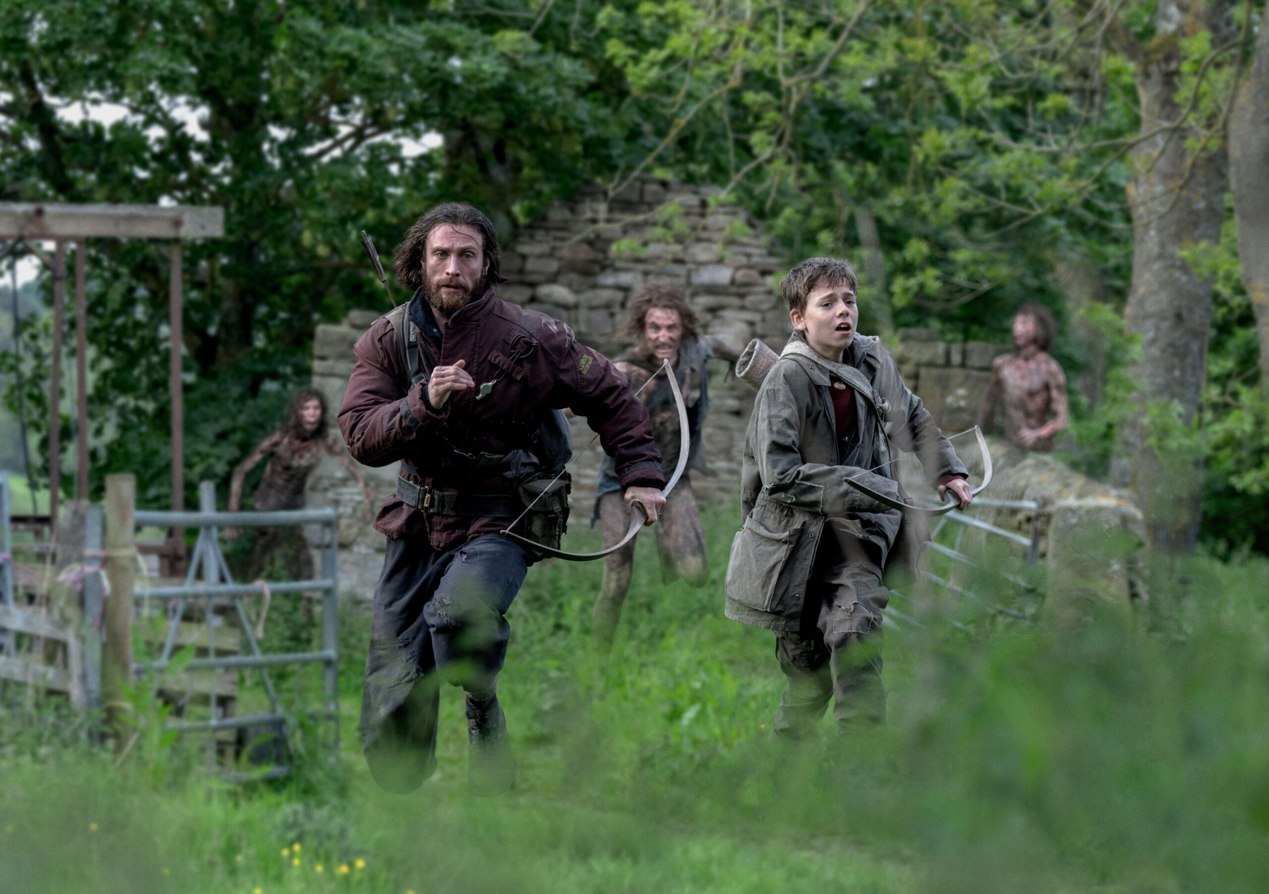 Aaron Taylor-Johnson and Alfie Williams running with bows and arrows, pursued by zombies.