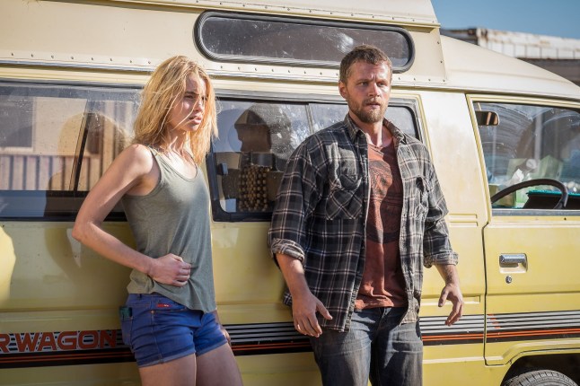 - Zombie Gaming Lucy Fry as Eve and Matt Levett as Kevin leaning against a van in Wolf Creek