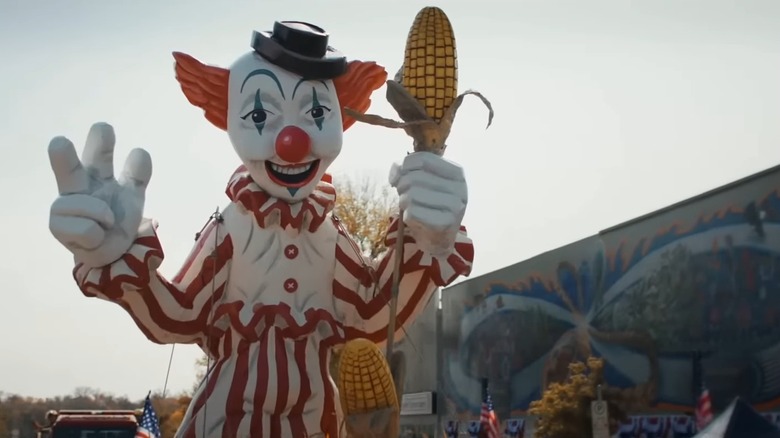 A clown statue holding an ear of corn, from Clown in a Cornfield
