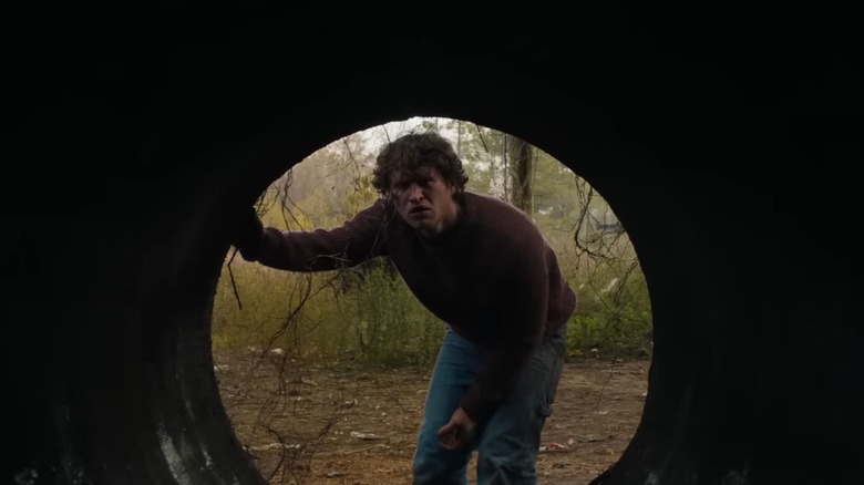 Rohan Campbell as Corey Cunningham in Halloween Ends, peering into a drainage tunnel