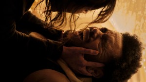 The Weeknd lies on the ground and screams as Jenna Ortega holds his face in a still from 'Hurry Up Tomorrow'