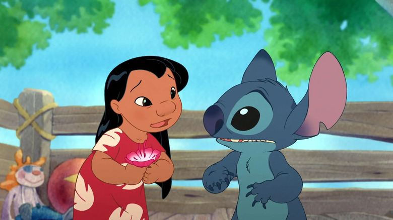 Small animated cartoon girl Lilo standing next to Sitch, a blue, animal-like alien creature in Lilo & Stitch 2: Stitch Has a Glitch