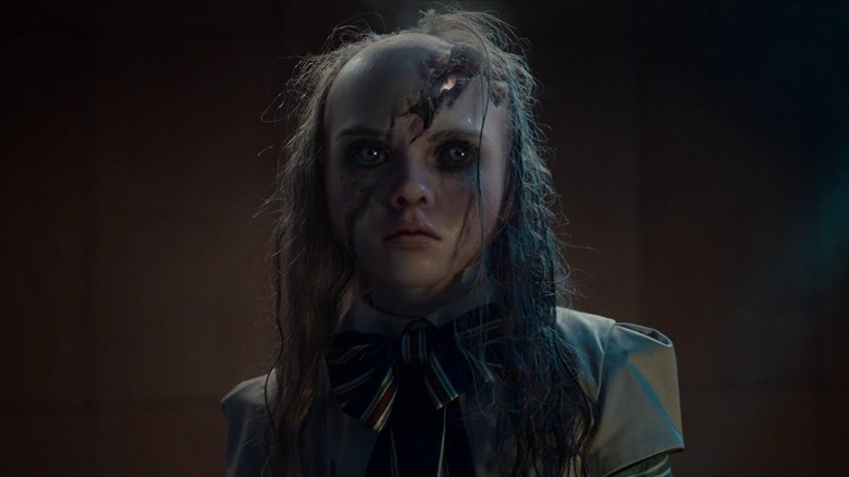 The M3GAN doll with her face cut and her hair burned in M3GAN