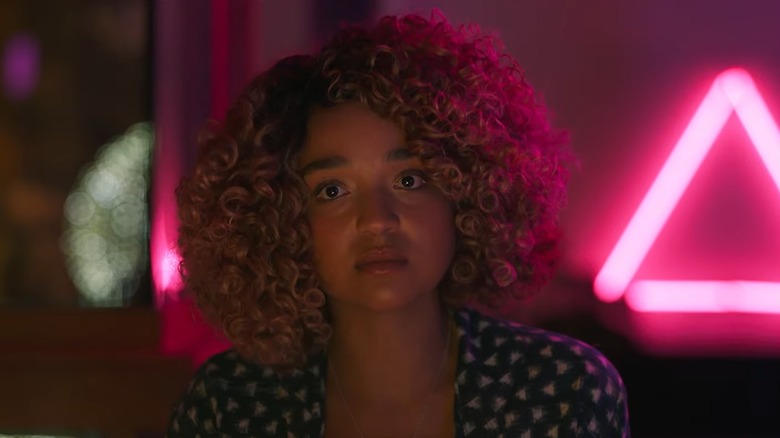 Aisha Dee as Sissy in Sissy, in front of a neon pink triangle